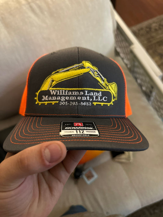 Gray and orange snapback hat embroidered with Williams Land Management LLC logo, company name, and phone number by Qwik Tees in DeLand FL 32724.